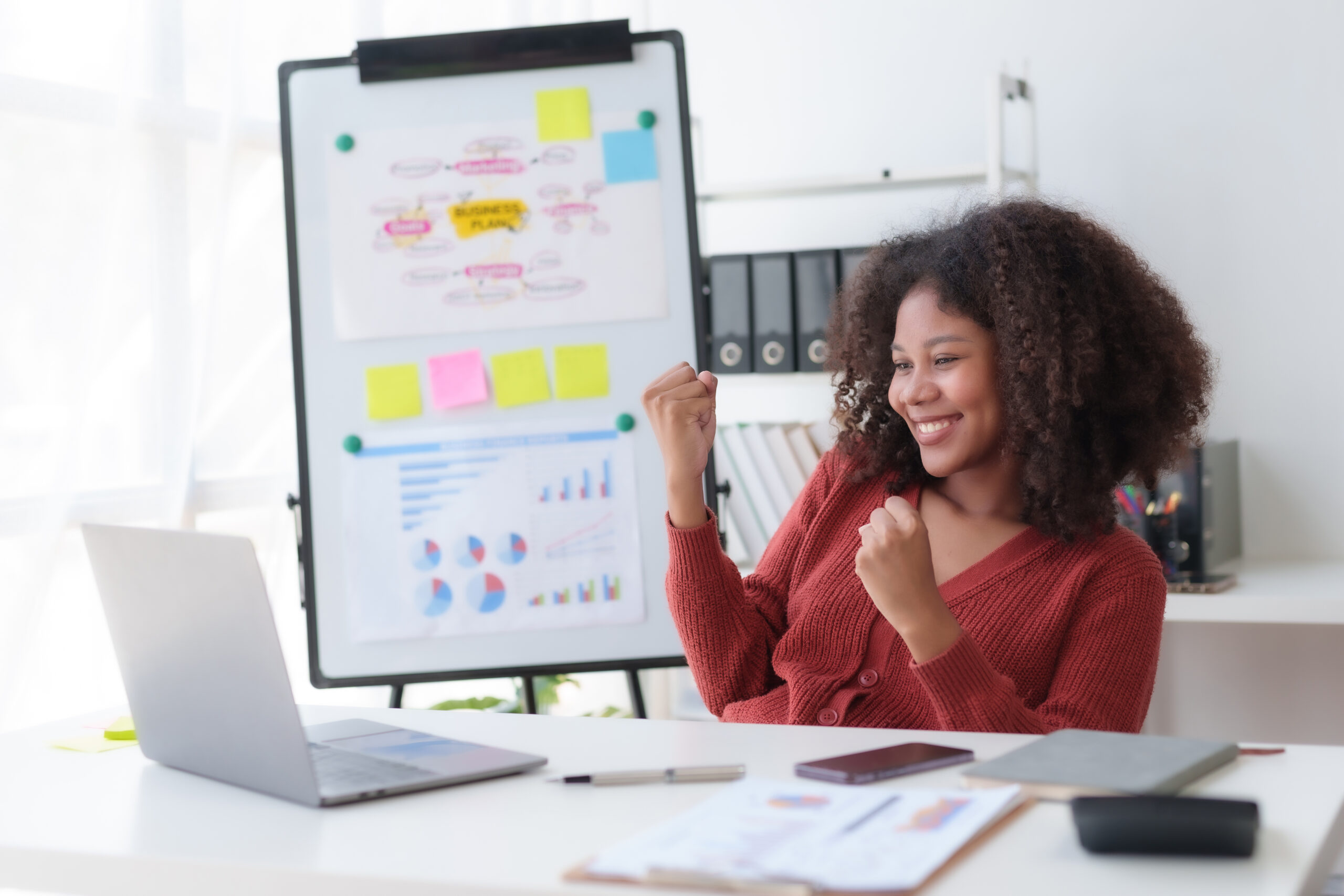 Happy businesswoman raising hands with victory smiling happily with laptop computer. The concept of success at work.